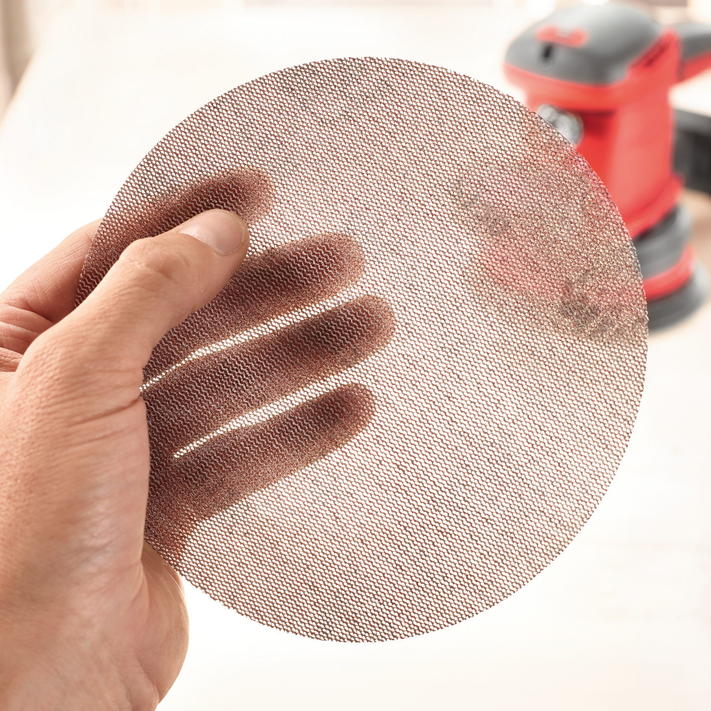 Abranet® setzt neue Maßstäbe. Rund 24.000 Löcher in der Schleifscheibe sichern eine optimale Staubabsaugung. Weitere Vorteile: eine höhere Standzeit der Schleifscheibe. Anwendungsbild, Rugbyball, Sport, Finger, Gesicht, Kopf